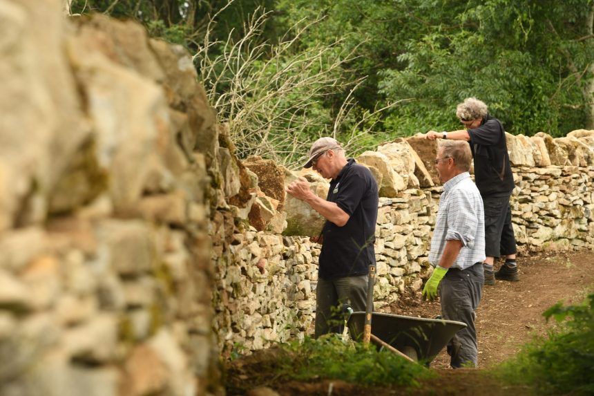 Three wardens repairing a traditional Cotswold dry stone wall