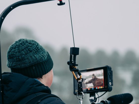 Image shows a person holding professional filming equipment, filming outside in the snow.