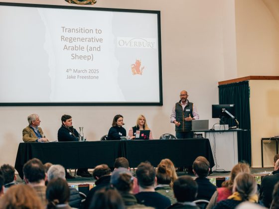 Image shows the Cotswolds Regenerative Agriculture Conference 2025 panel members, speaking to a full audience.